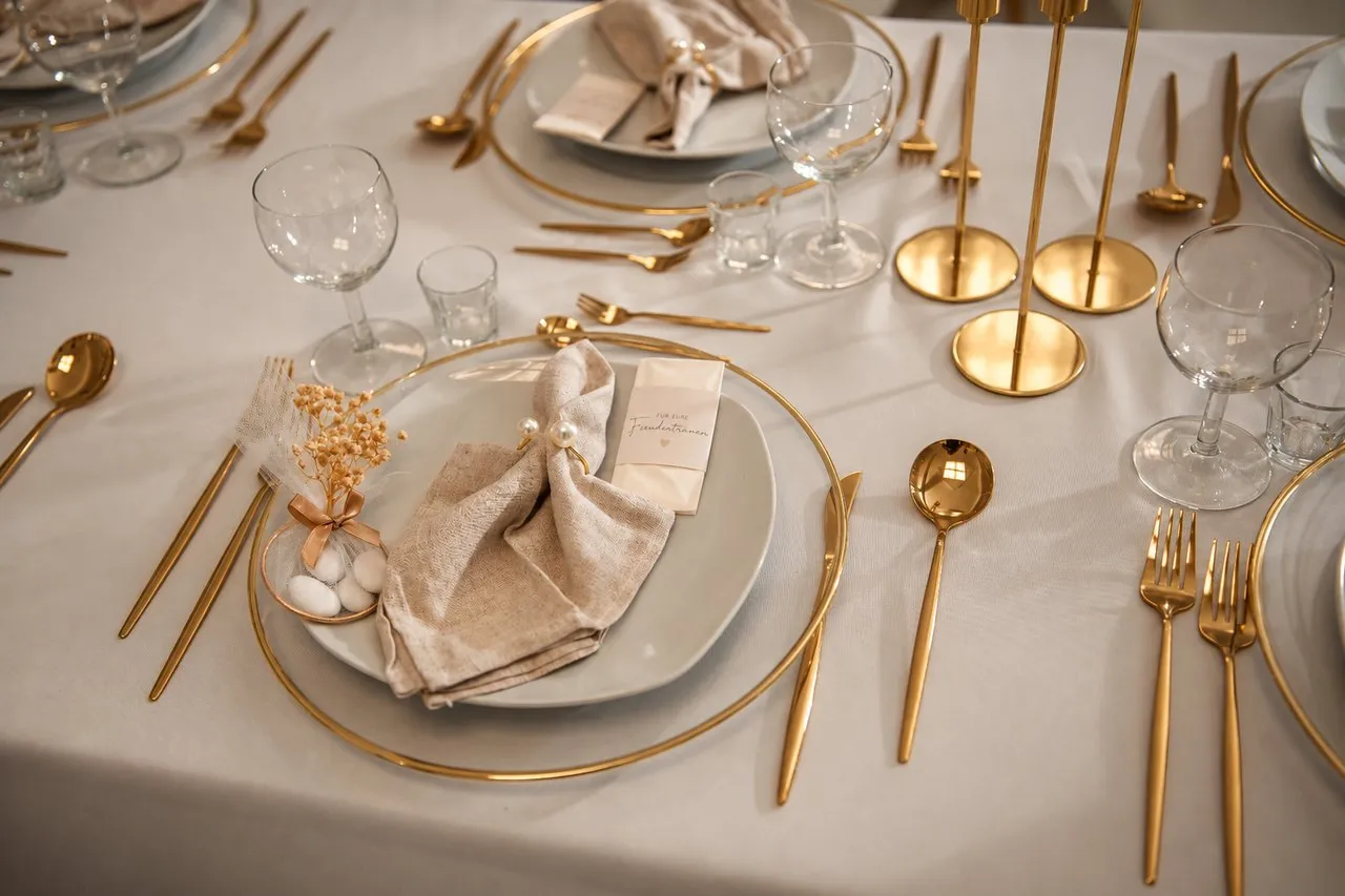 Gedeckter Hochzeitstisch mit Goldbesteck und Platztellern